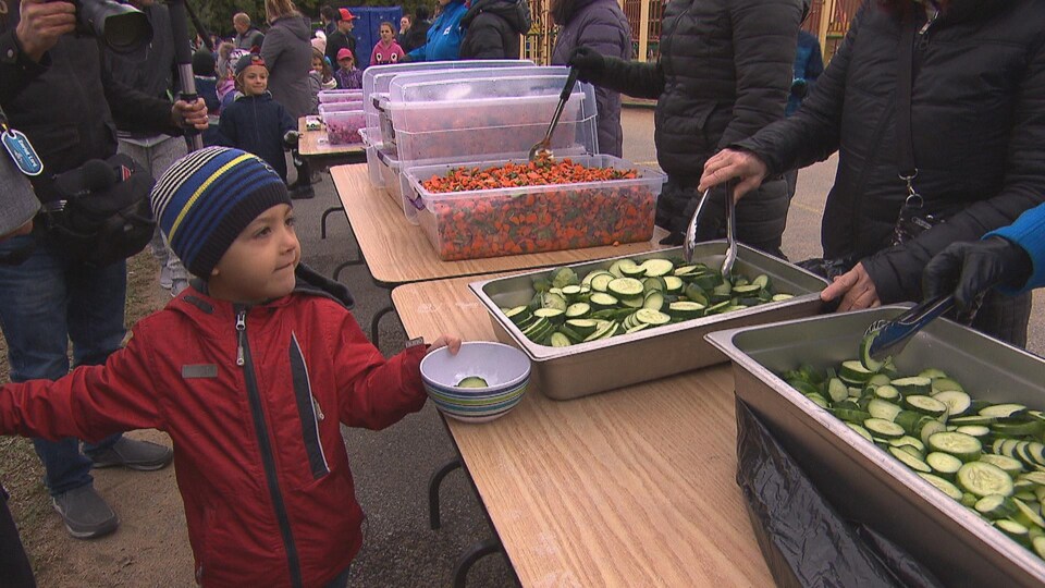Jeune enfant qui se fait servir des concombres.