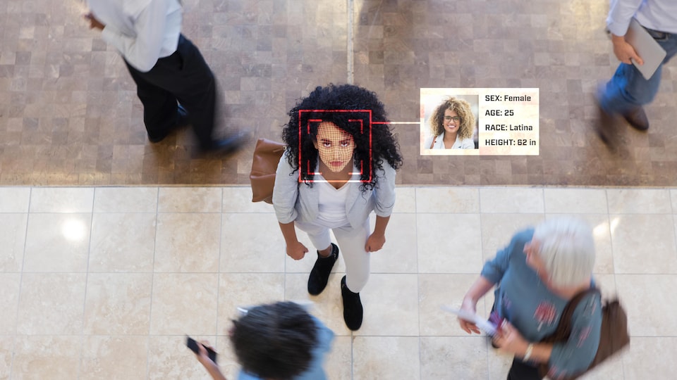 Une femme regarde une caméra qui scanne son visage et un logiciel lui colle plusieurs critères de reconnaissance.