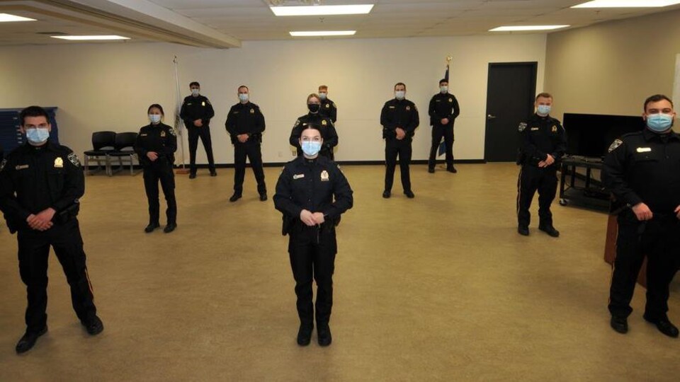 Onze policiers se tenant debout dans une salle.