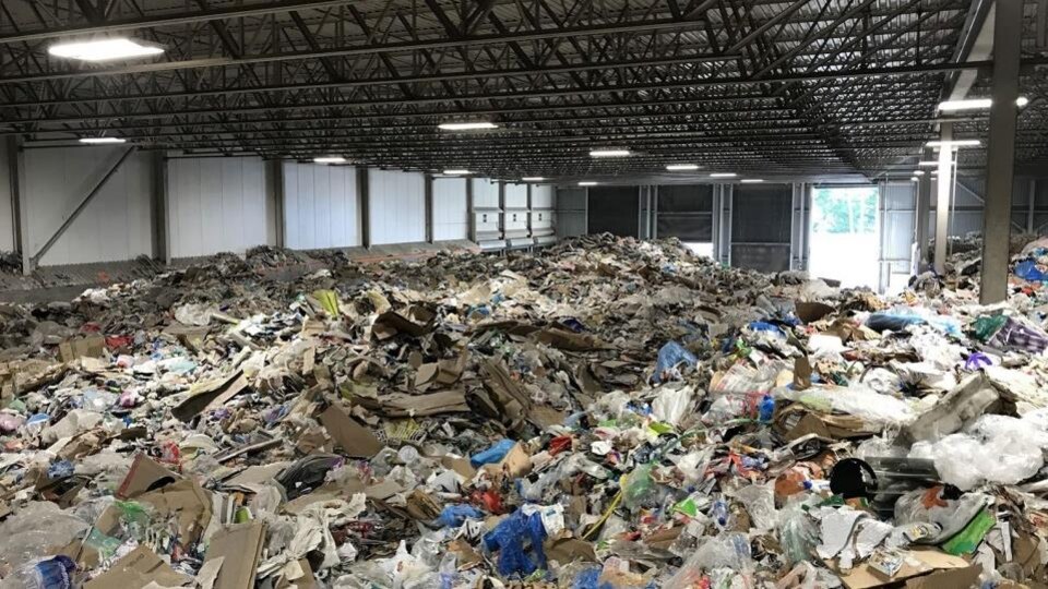 Photo de l'intérieur du centre de tri de Lachine. Du carton et du plastique s'accumulent.