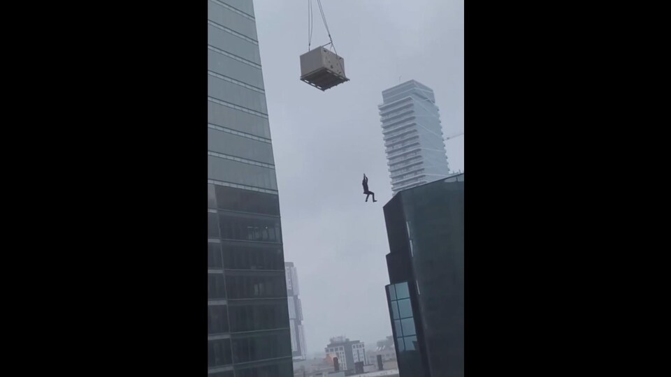 Un homme suspendu dans les airs près de gratte-ciel.