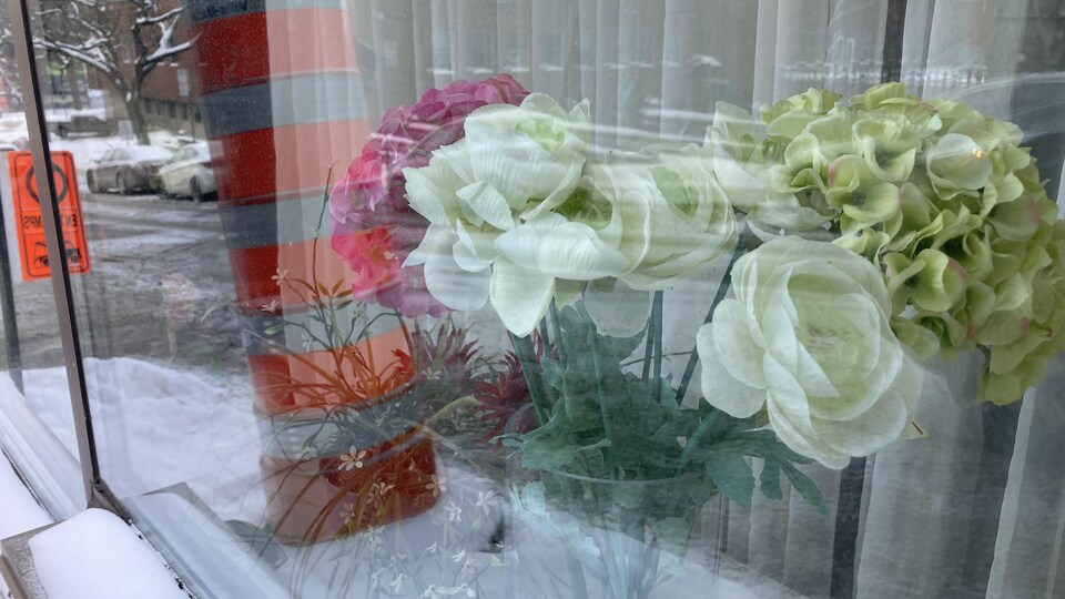 Un bouquet de fausses fleurs derrière une vitre de l'hôtel.