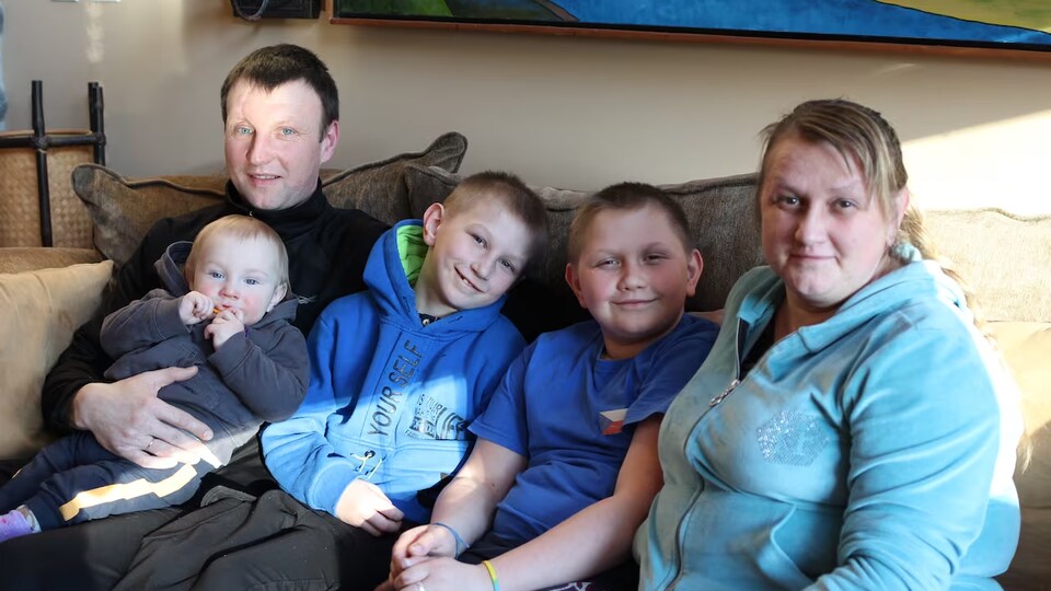 Une famille assise sur un divan.