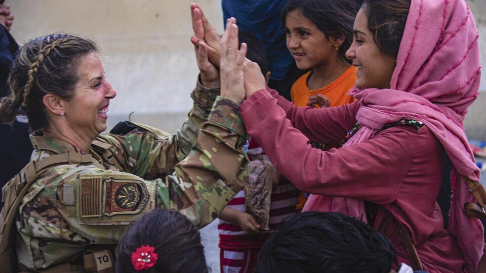 Une militaire tape dans les mains d'une jeune Afghane.