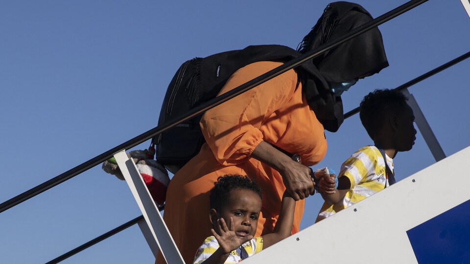 Une femme et deux enfants montent à bord d'un avion.