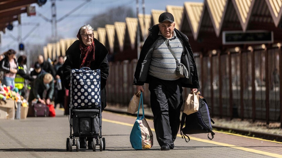 Ukrainian refugees walk on the platform of a train station in Poland.