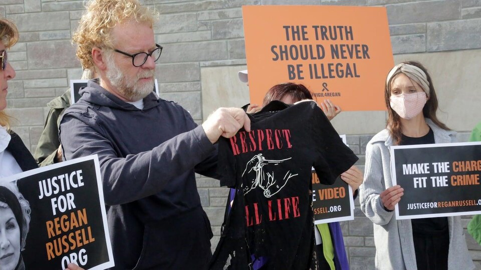 Un homme tient un t-shirt noir