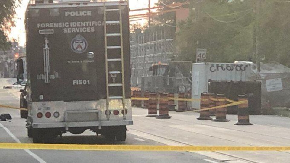 Un camion de police et des banderoles jaunes bloquent la rue.