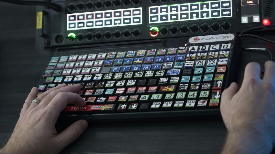 A man's hands on a console in a television studio.