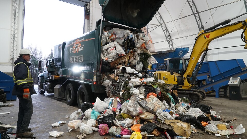 Un homme se tient debout près des déchets qui tombent d'un camion lors du déchargement.