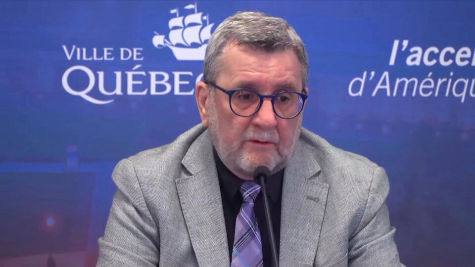 Régis Labeaume devant le logo de la ville de Québec en conférence de presse. 