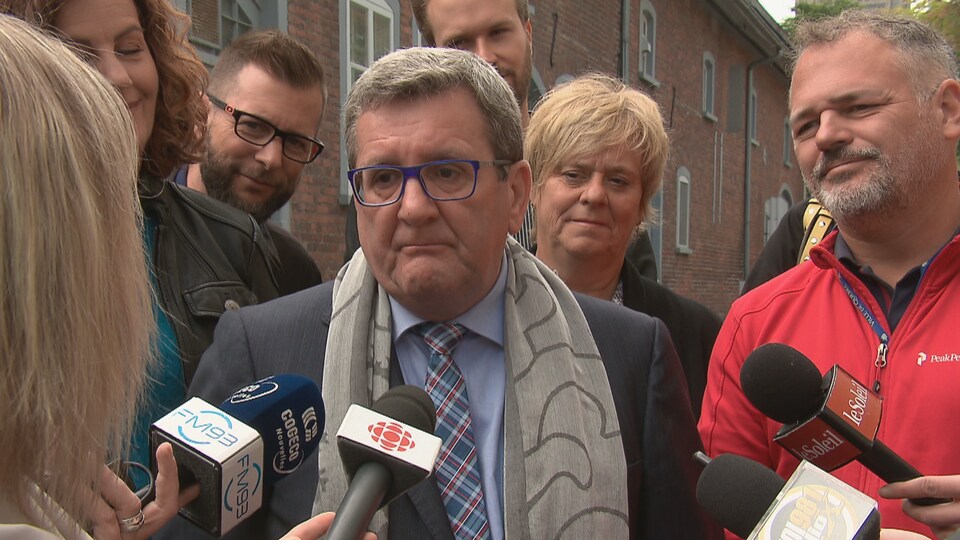 Régis Labeaume répond aux questions des journalistes lors d’une mêlée de presse, entouré de candidats de son équipe.