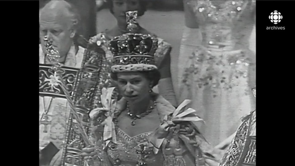 La reine Élisabeth II, sceptre à la main et lourde couronne sur la tête, en procession à la suite de son couronnement.