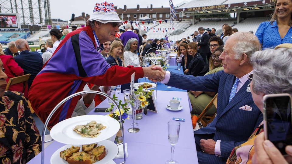 Prince Charles shook hands with a man behind the dining room table.