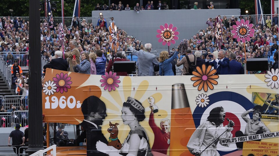 People on the roof of the bus showing pictures of the 70 -year reign of Queen Elizabeth II.