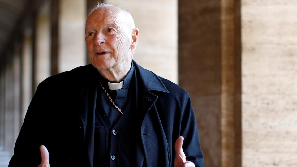 Un vieil homme portant l'habit d'un cardinal dans un corridor.