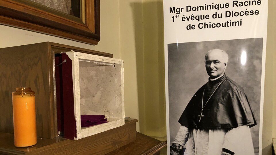 Le présentoir où la relique a été volée, à côté d'une affiche montrant Mgr Dominique Racine.