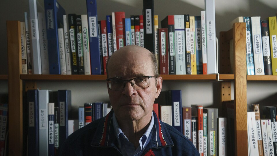 Un homme devant sa bibliothèque.