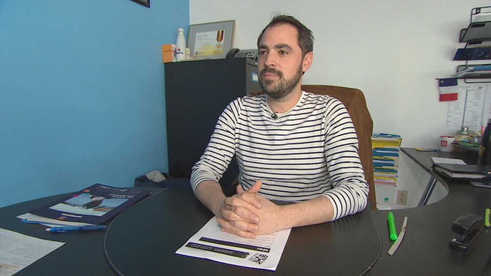 Un homme assis derrière son bureau.
