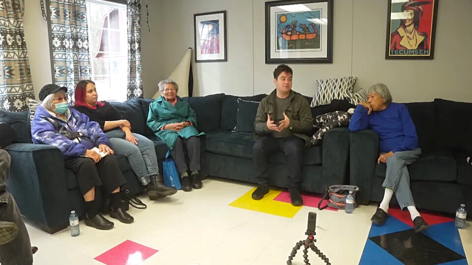 Quatre membres de la Première Nation de Walpole Island, assis dans un salon, écoutent leur invité Arieh Smith.
