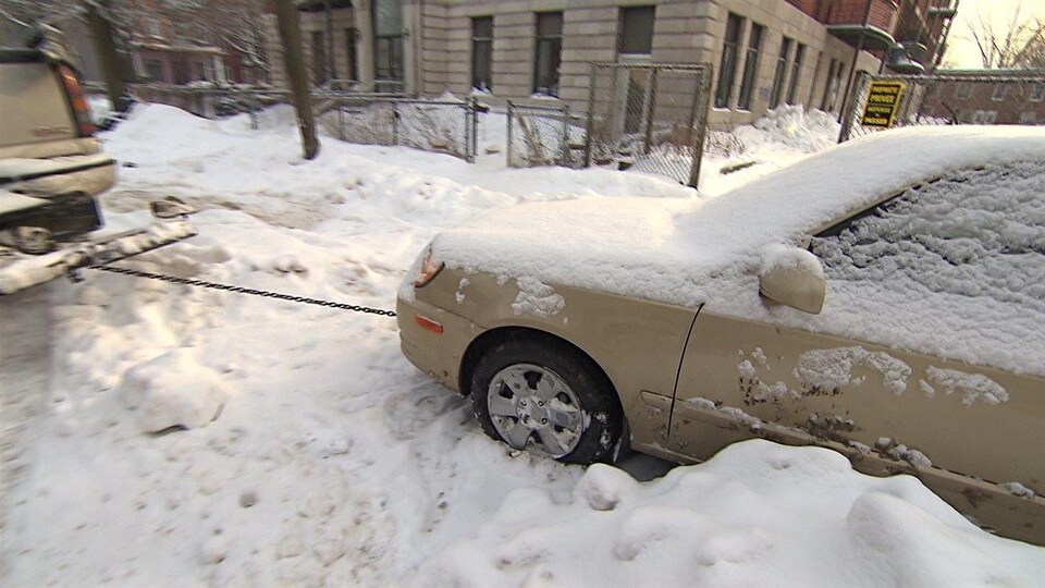 Une voiture se fait remorquer à Montréal durant une opération de déneigement.