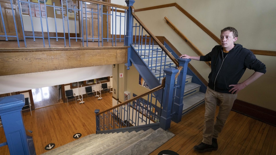 Rémy Robitaille stands on the landing of a staircase, in a community center in Montreal.