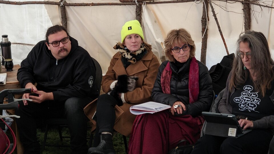 Les trois personnes sont assises dans une tente.
