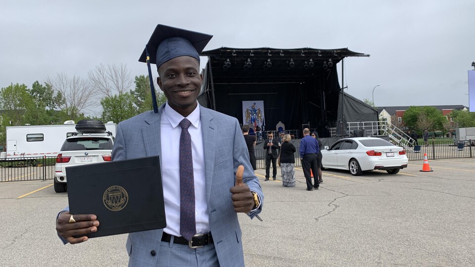 René Douvon, son diplôme à la main, sur le parc de stationnement devant l'Université Mount Royal.