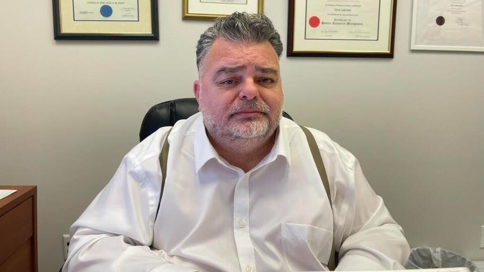 René Labrosse est assis devant son ordinateur portable et des documents.