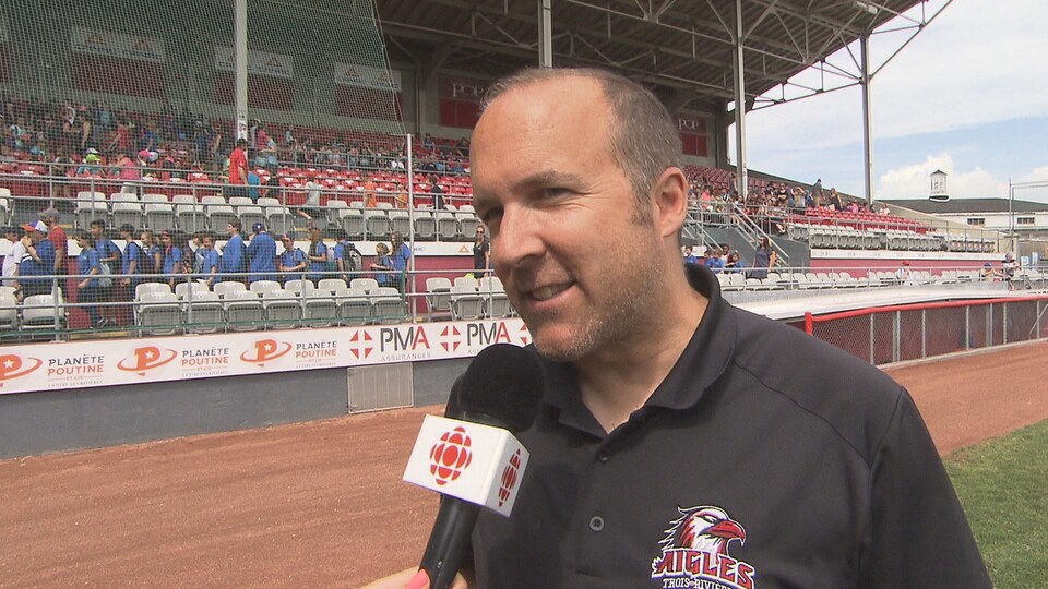 Sur le terrain de baseball, il répond aux questions de la journaliste.