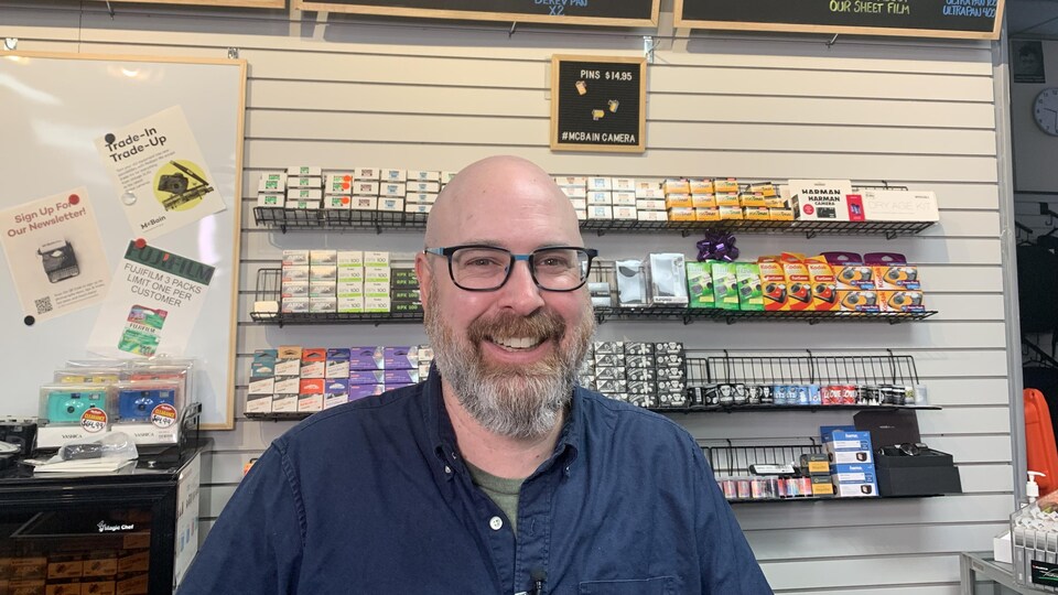 Rene Rodrigue behind the counter selling film negatives at McBain Camera.