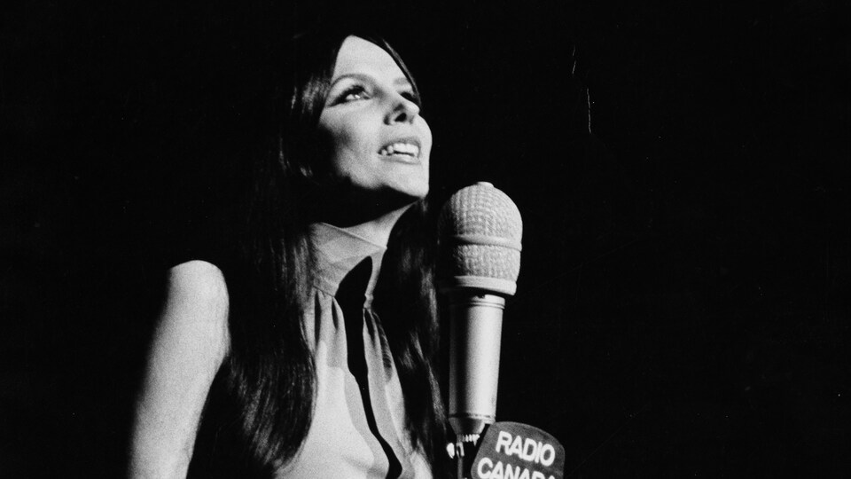 Renée Claude derrière un micro.
