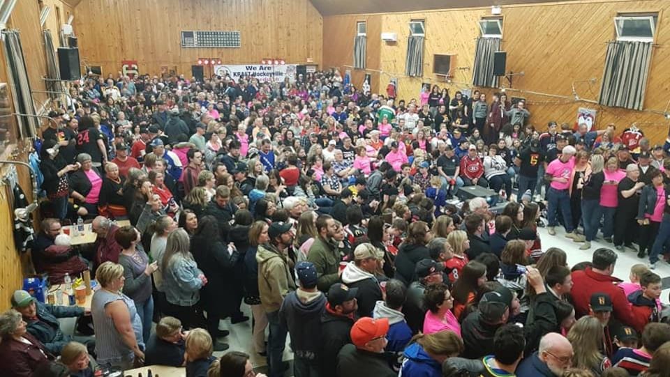 Une centaine de citoyens sont entassés dans une salle communautaire et attendent une annonce.