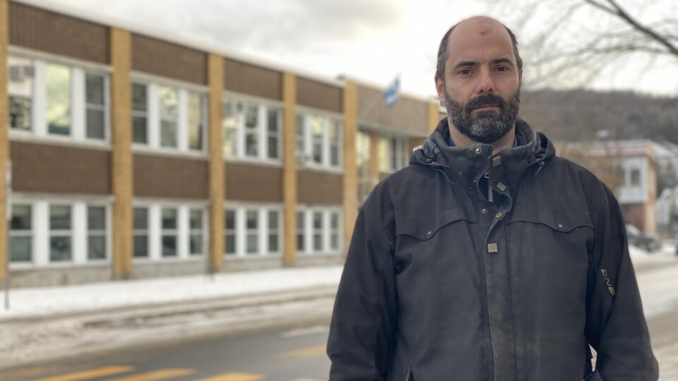 Un homme pose devant une école primaire.