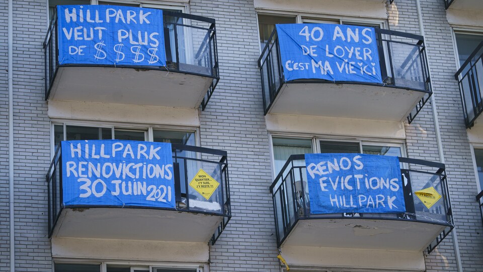 Des pancartes de contestation installées sur des balcons de logements d'un immeuble.