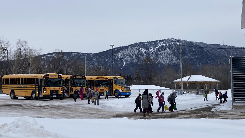 Des enfants marchent de l'autobus scolaire à l'école.