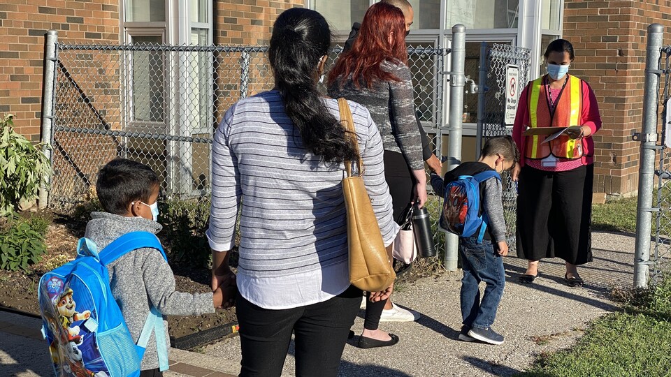 De jeunes élèves et leurs parents arrivent à l'école.