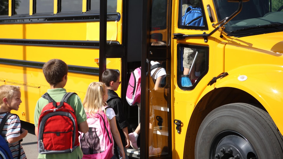 Des élèves montent à bord d'un autobus scolaire.