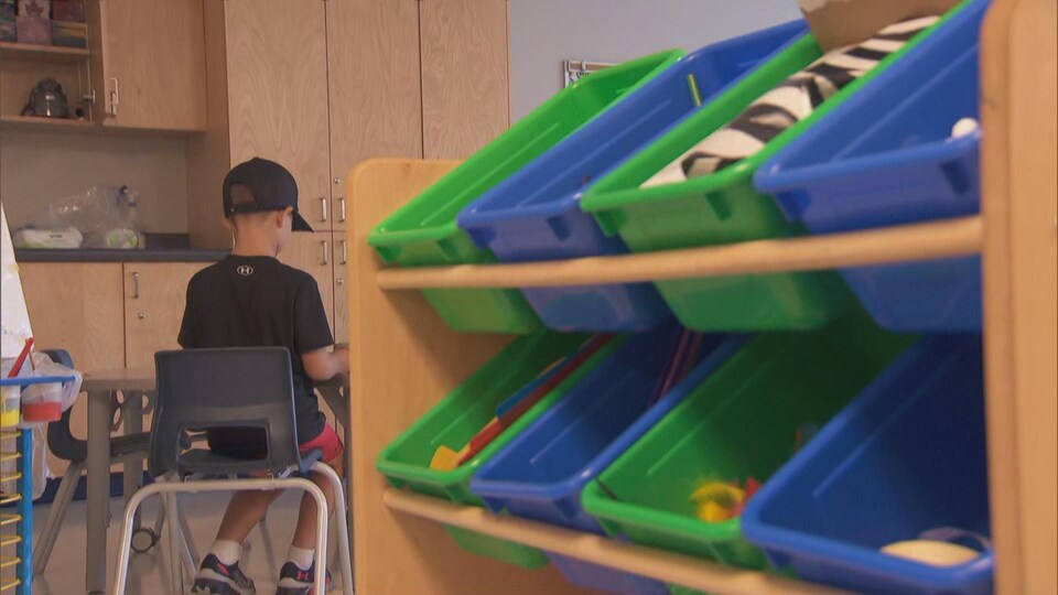 Un enfant, de dos, joue dans sa classe.