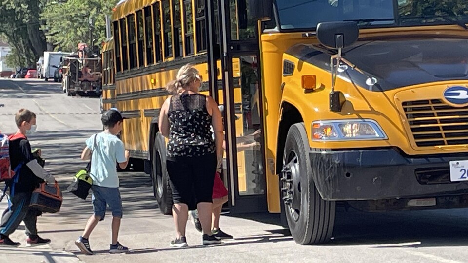 Des enfants montent dans un autobus scolaire.