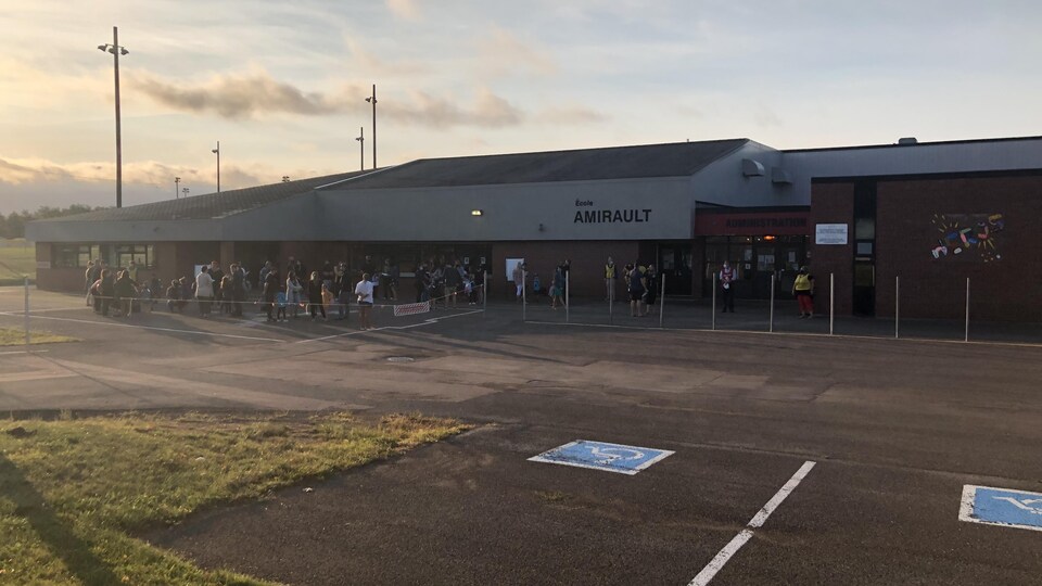 Une file d'attente devant l'école Amirault alors que le soleil se lève.