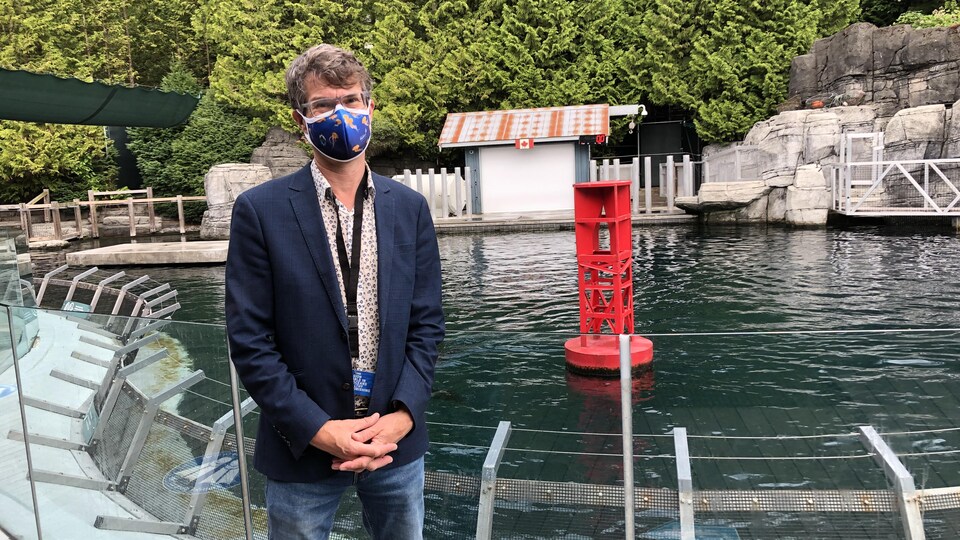 Peter Ross, portant un masque, devant un bassin de l'aquarium de Vancouver.