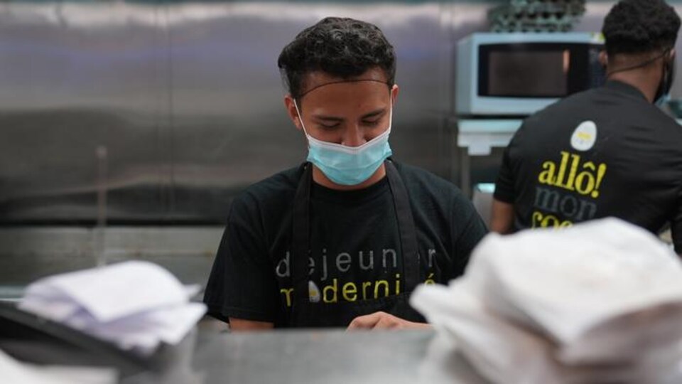 Des employés masqués effectuent des préparatifs en vue de la réouverture des salles à manger, lundi.