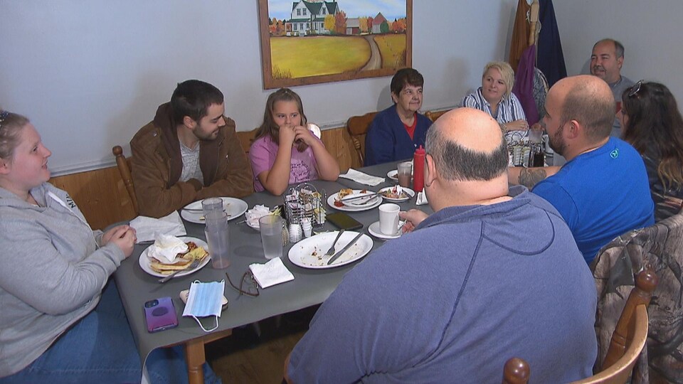 Des membres d'une famille, allant des adultes aux plus jeunes, sont attablés ensemble.