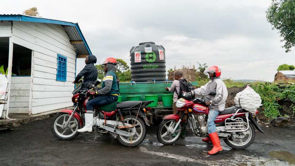 Des motocyclistes sont arrêté près d'une cabane. Un homme se lave les mains.