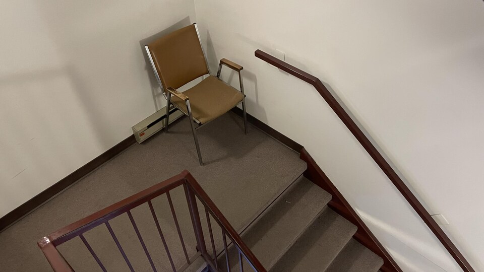 Une chaise sur un demi-étage d'escalier.