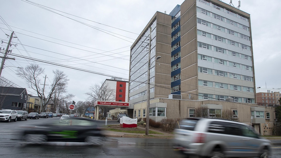 Des voitures circulent devant un bâtiment d'une dizaine d'étages.