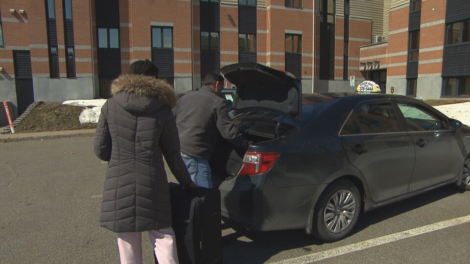Une femme dépose sa valise dans un taxi.