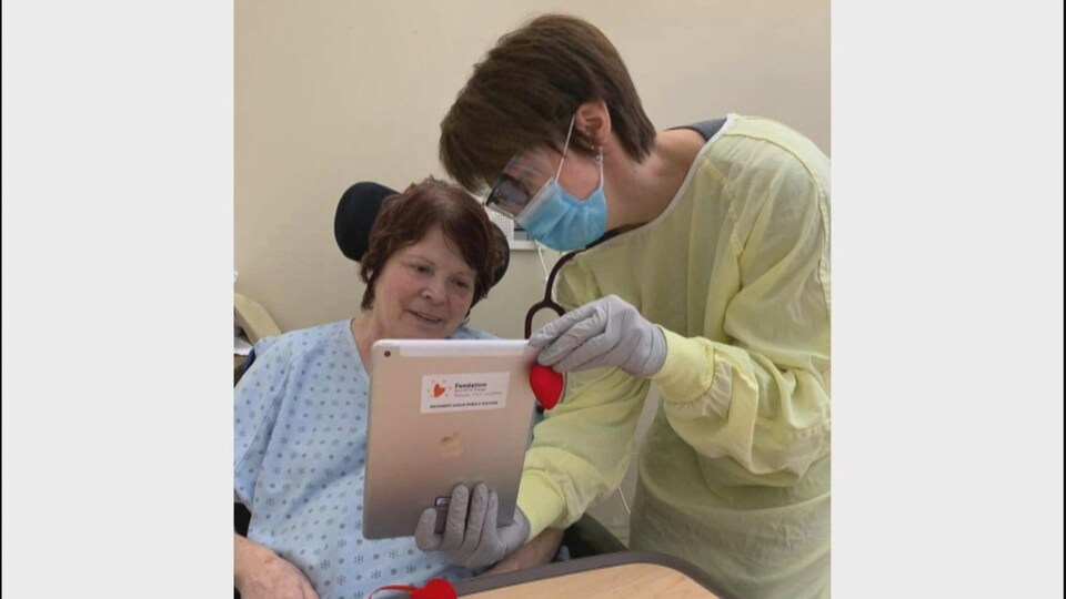 Une infirmière tenant une tablette électronique devant une résidente du CHSLD Laflèche.