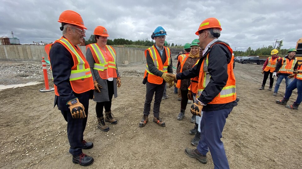 Rémi Lalonde serre la main d'un travailleur sur le chantier, sous le regard amusé de quelques personnes.